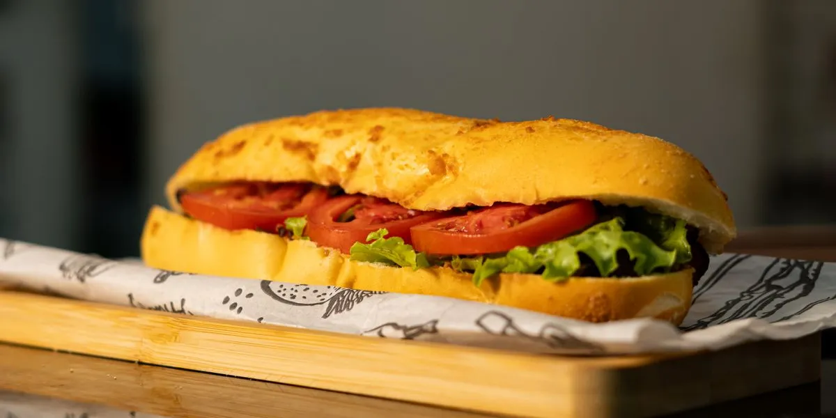 A sub sandwich with tomato and lettuce on a wooden board — decorative stock image