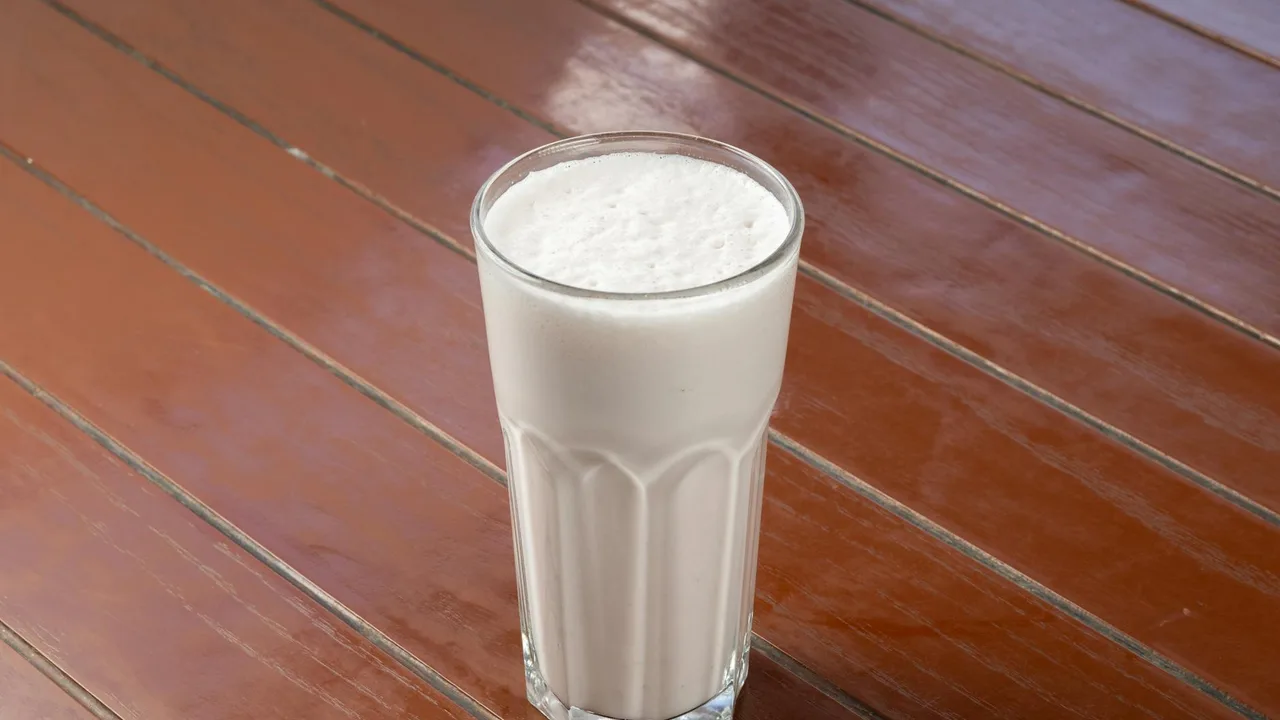 A creamy vanilla milkshake in a glass on a wooden table, perfect for refreshment.