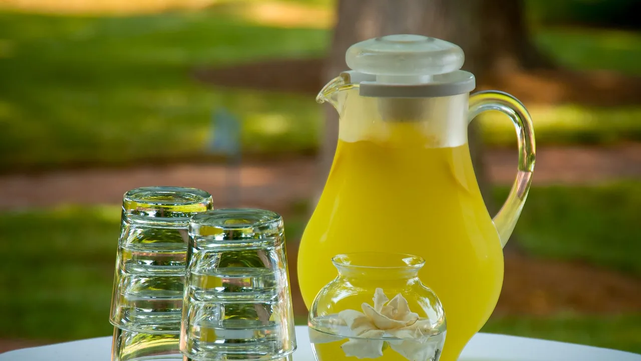 A pitcher of lemonade with glasses set outdoors on a sunny day, perfect for a refreshing drink.