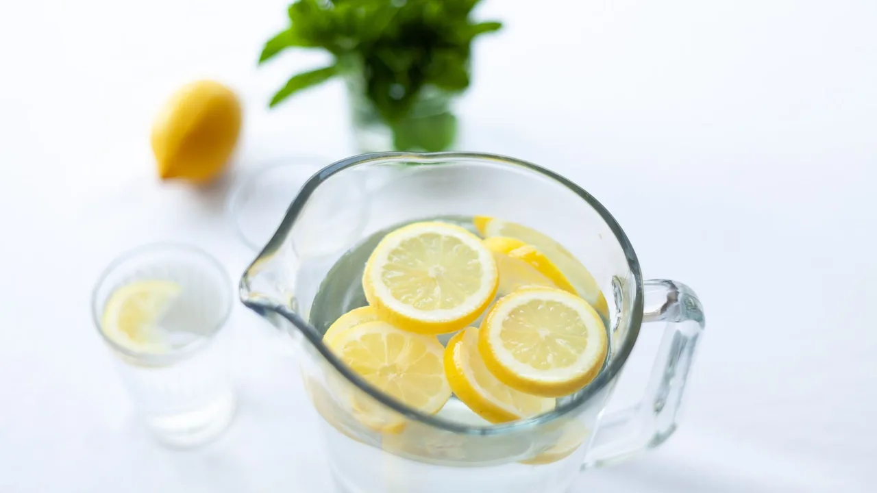 Top-down view of lemon slices in a glass pitcher filled with water, offering a refreshing drink option.