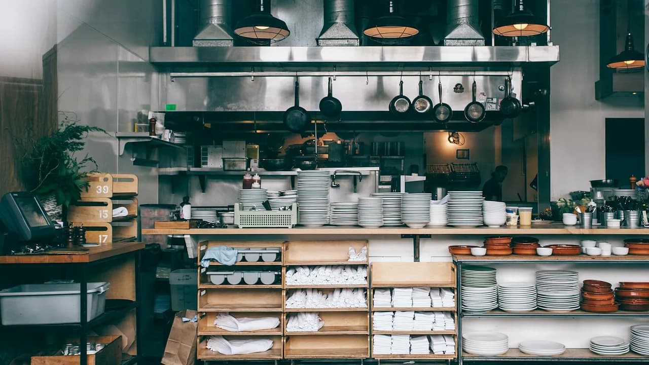 Interior of kitchen in modern restaurant with piles of plates and other different assorted utensils