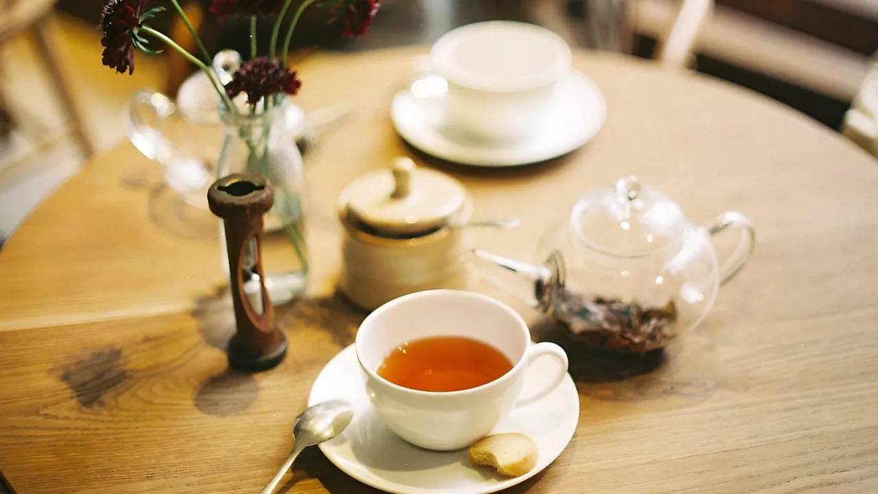 Elegant table setup with a cup of tea, cookie, and flowers, providing a cozy atmosphere.