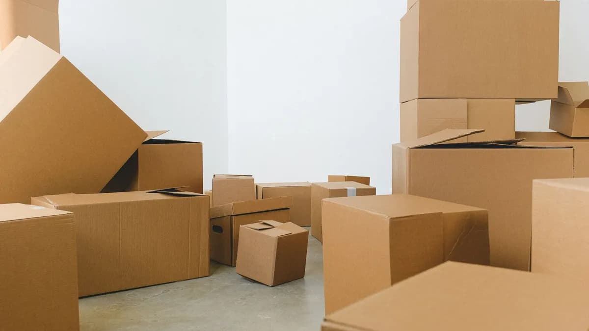 Stack of carton boxes of various shapes and sizes scattered in floor near white walls during relocation