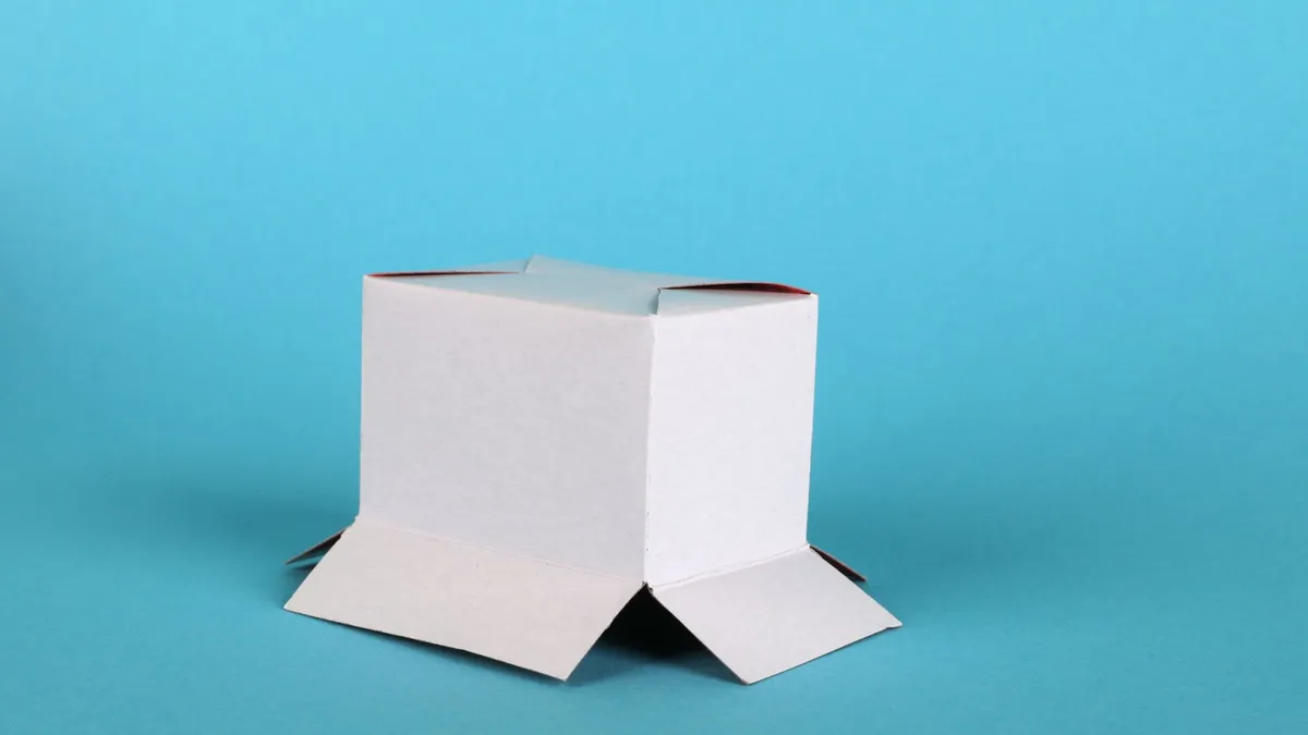 White cardboard box with open flaps on a blue backdrop, perfect for packaging or presentation themes.