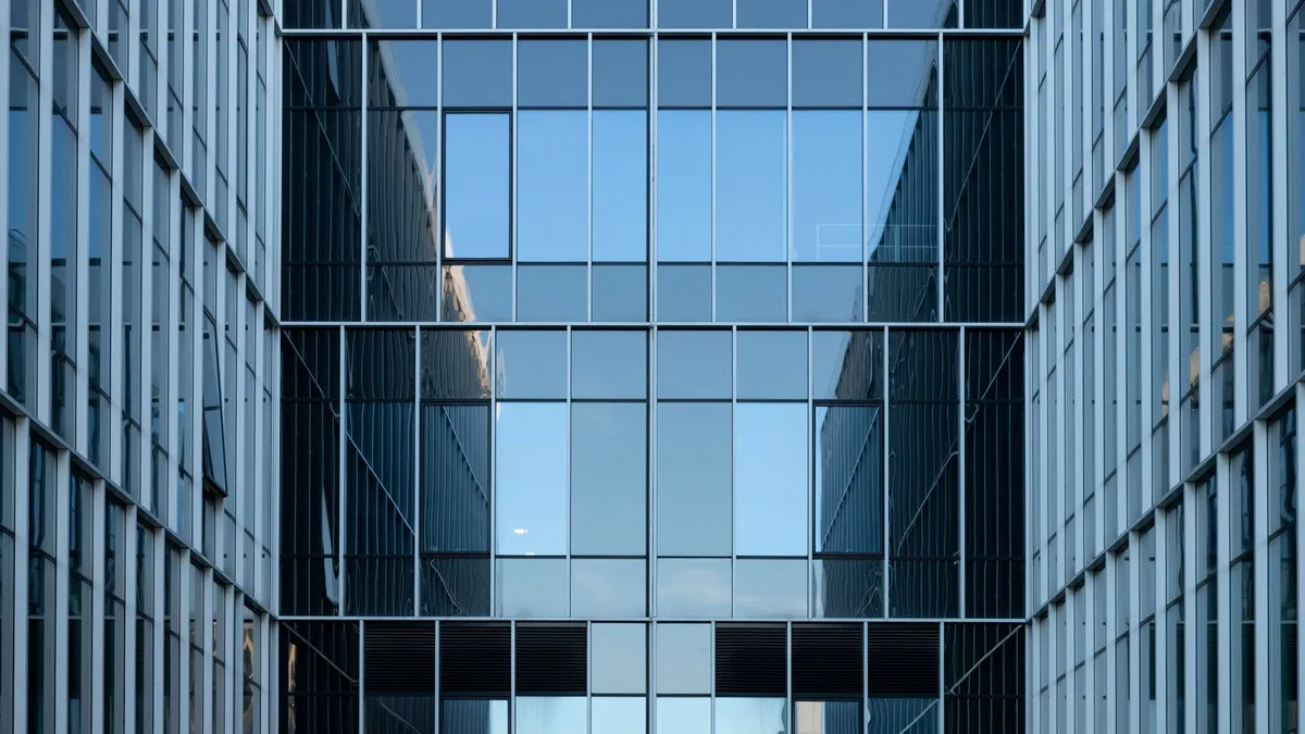 Contemporary building facade with reflective glass windows in an urban environment.