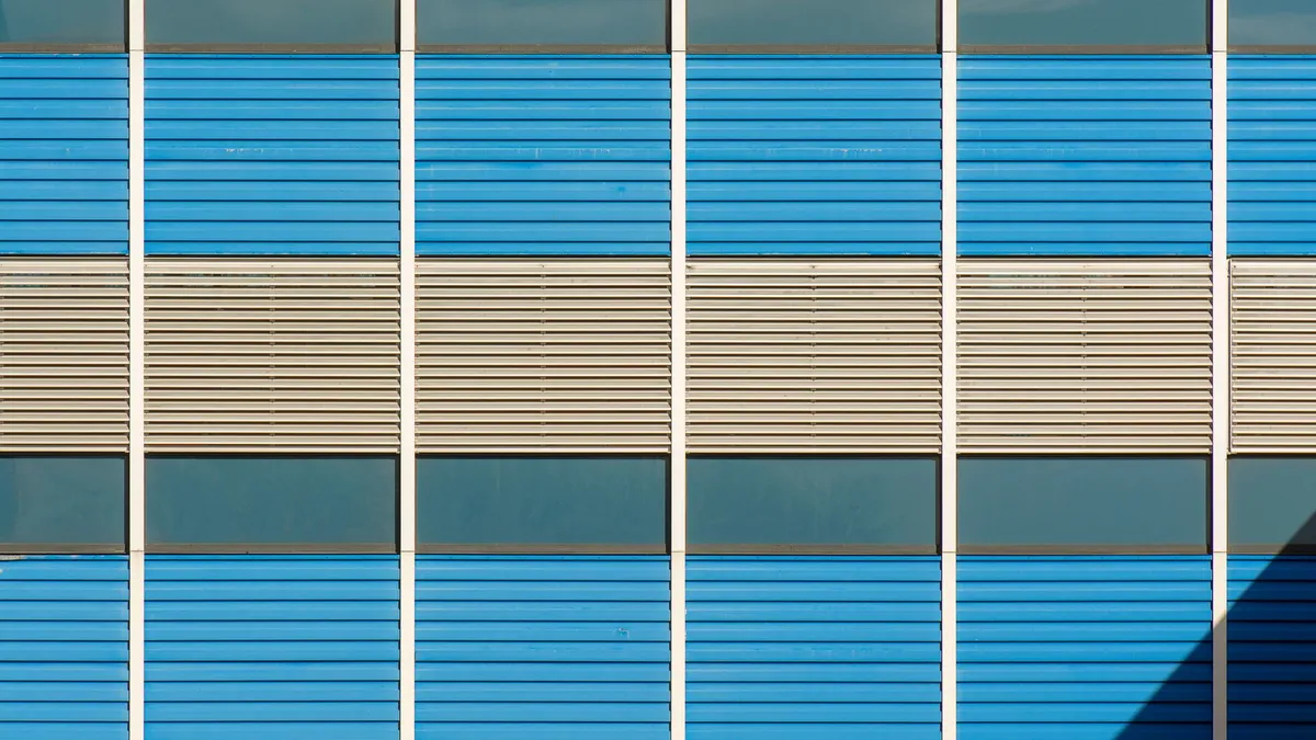 Close-up of a modern building facade featuring blue and beige panels in geometric patterns.