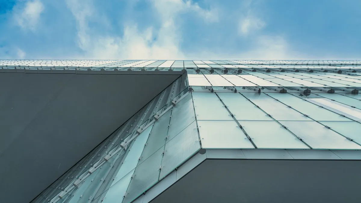 Contemporary glass facade in Oslo against blue sky, showcasing urban architectural design.