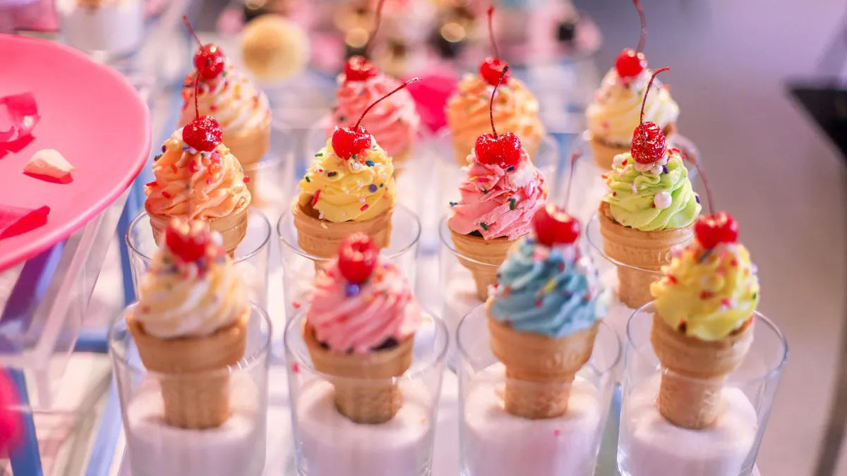 Vibrant ice cream cones with cherries and sprinkles in glass cups, perfect for a sweet treat.