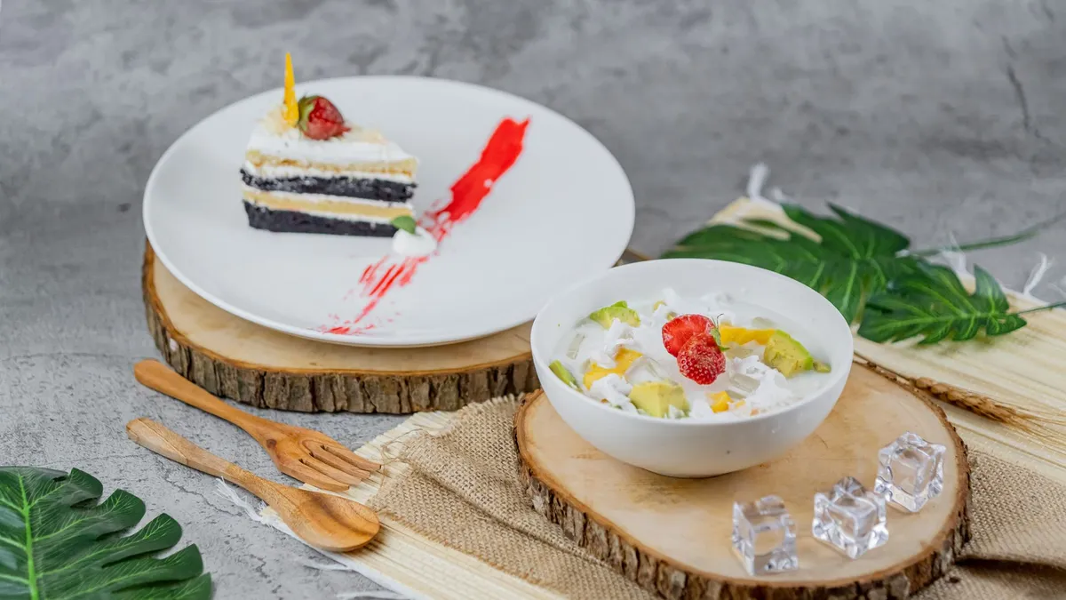 A decorative display featuring a chocolate layered cake and a bowl of tropical fruit salad with vibrant presentation.