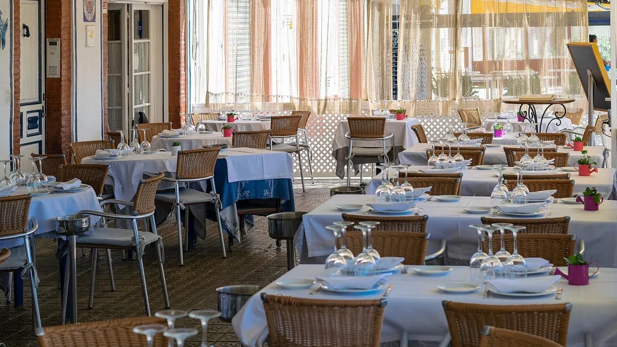 Charming outdoor dining area with neatly set tables in Sitges, Spain, bathed in natural light.